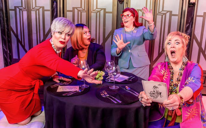 Women at a table reacting humorously during Menopause the Musical performance.
