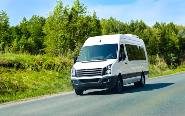 Minibus on road for Gjirokaster day tour transfers.
