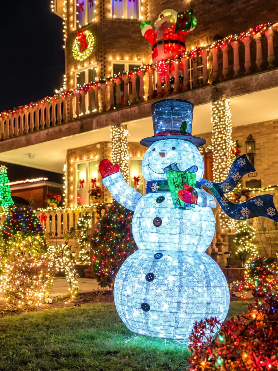 Snowman and Santa decorations with festive lights on Dyker Heights Christmas Lights Bus Tour.