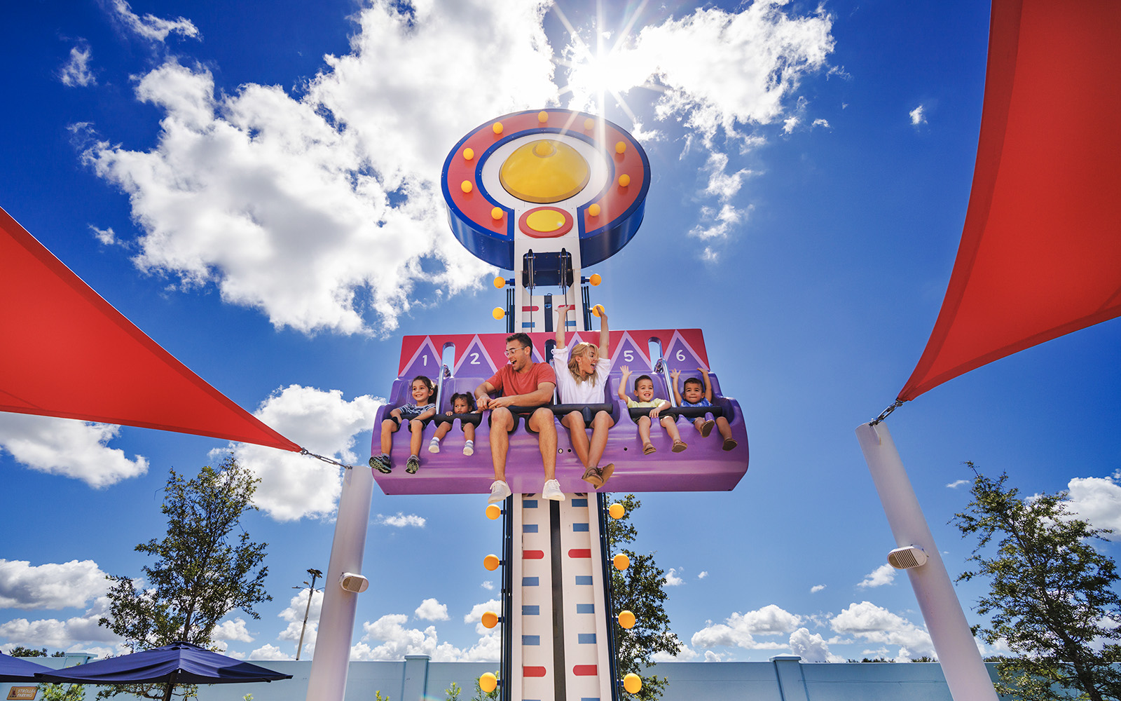 Visitors enjoying a ride at Peppa Pig Theme Park, Florida under a sunny sky.