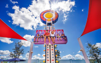 Visitors enjoying a ride at Peppa Pig Theme Park, Florida under a sunny sky.