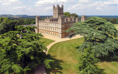 Highclere Castle surrounded by lush gardens, featured in Downton Abbey tours.