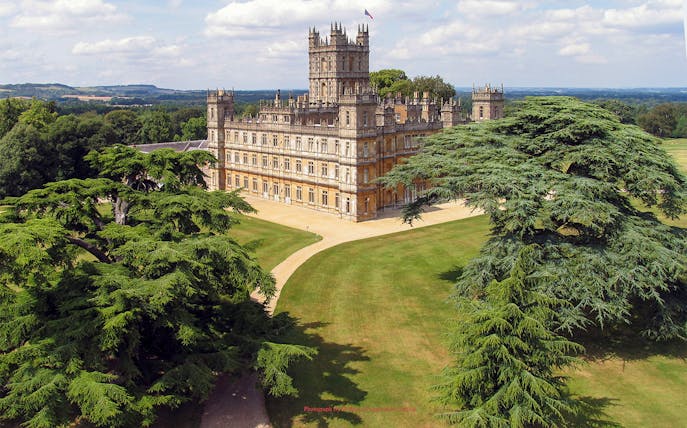 Highclere Castle surrounded by lush gardens, featured in Downton Abbey tours.