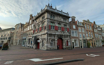 Historic building with red shutters on a cobblestone street in Haarlem, part of the self-guided city exploration game.