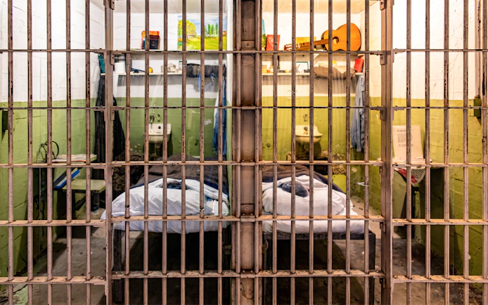 Alcatraz prison cell interior with bed and personal items on display.