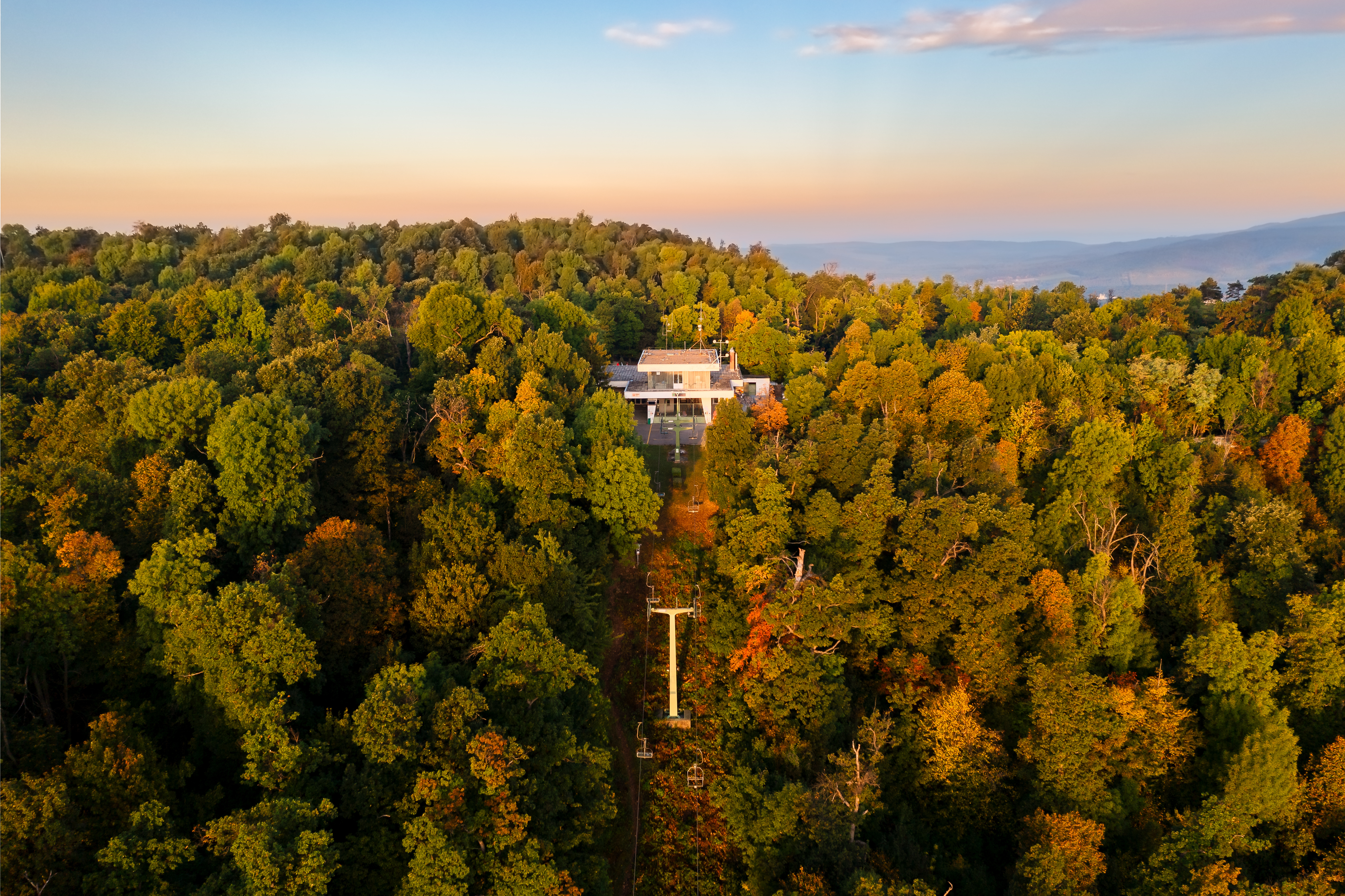 Aerial view of Zugliget chairlift station surrounded by lush forest in Budapest.