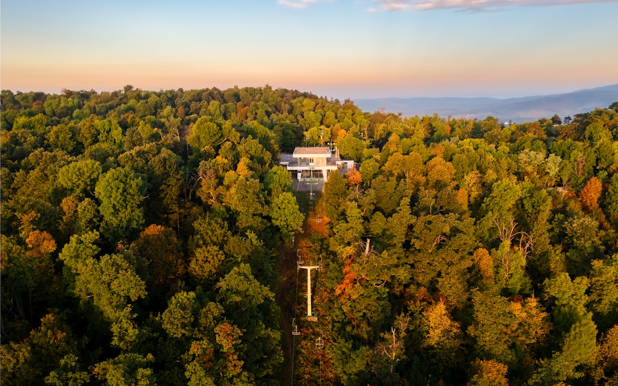 Aerial view of Zugliget chairlift station surrounded by lush forest in Budapest.