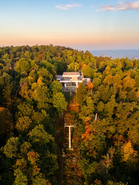 Aerial view of Zugliget chairlift station surrounded by lush forest in Budapest.
