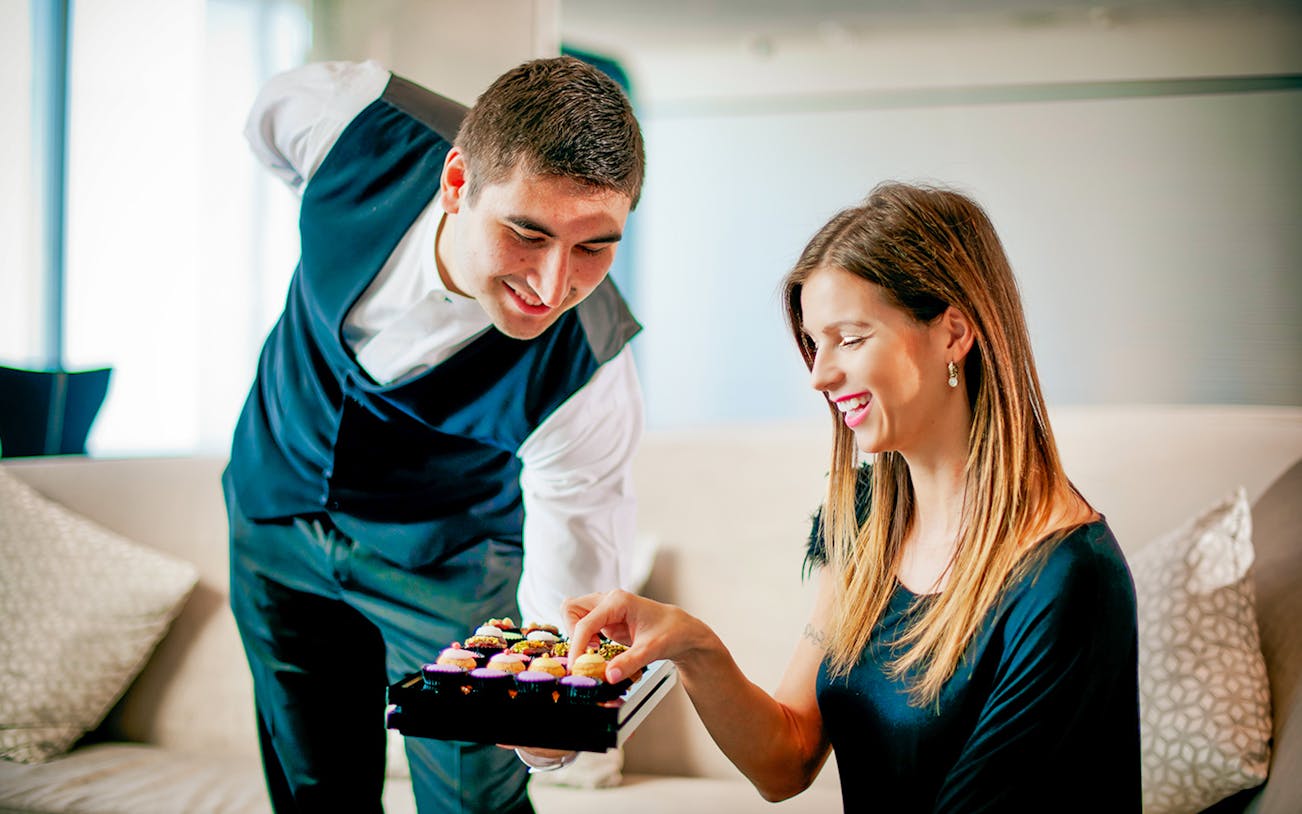 Server offering desserts to a guest at Burj Khalifa observation deck cafe, Abu Dhabi transfer included.