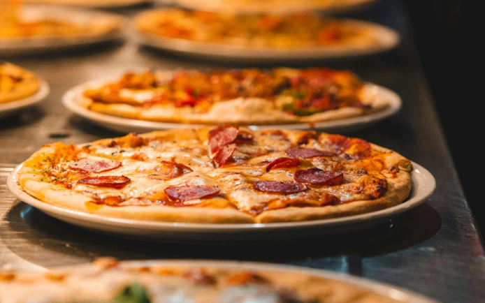 Pepperoni pizzas on plates, served on a cruise dining table.