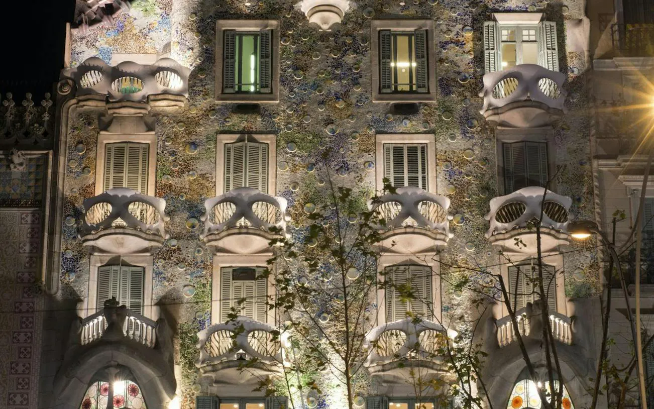 Facade of Casa Batlló, a Gaudí-designed building in Barcelona, illuminated at night.