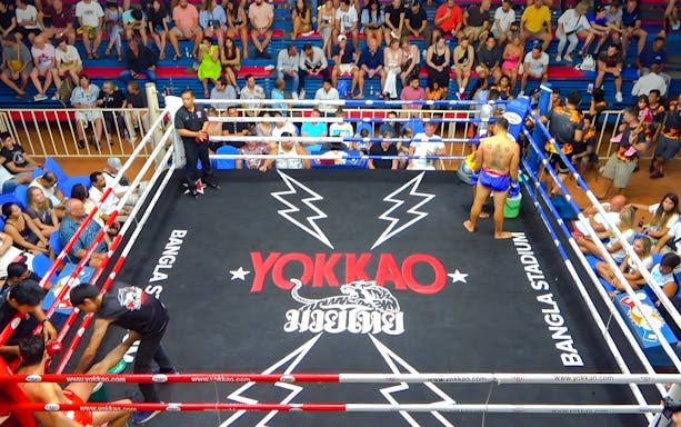 Muay Thai match at Bangla Boxing Stadium with a fighter in the ring and audience watching.