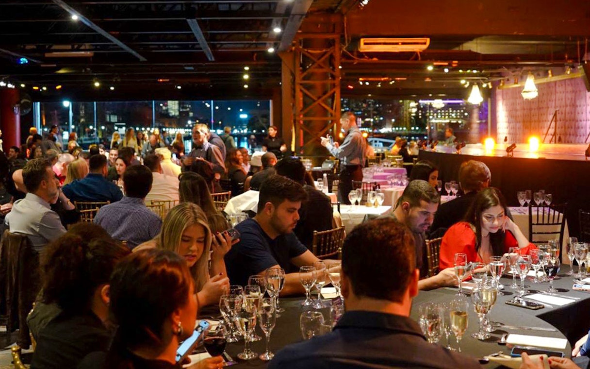 Guests dining at Madero Tango Show in Buenos Aires, with a stage and city lights in the background.