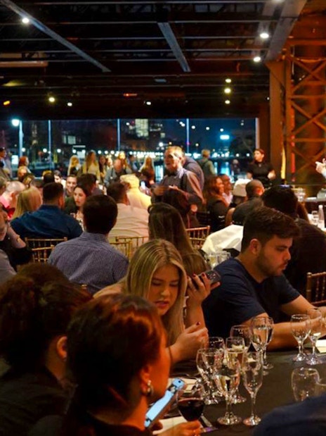 Guests dining at Madero Tango Show in Buenos Aires, with a stage and city lights in the background.