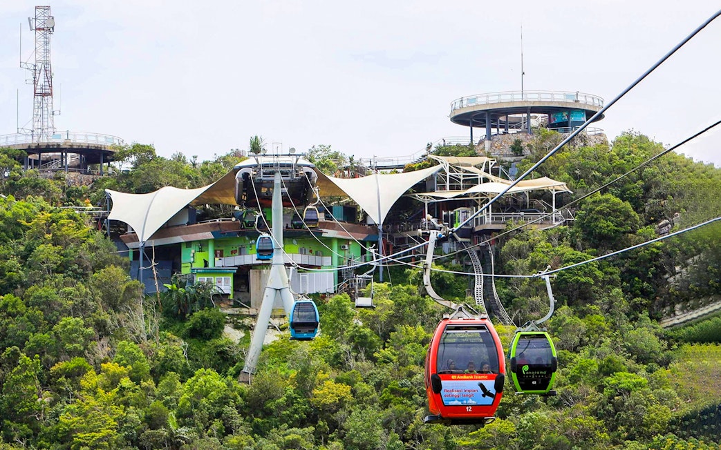 SkyCab cable cars ascending over lush greenery in Langkawi, Malaysia.