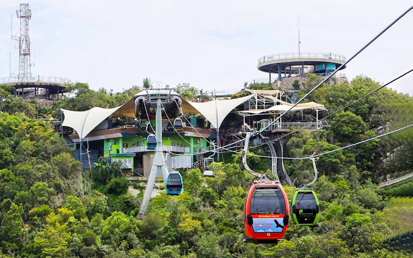 SkyCab cable cars ascending over lush greenery in Langkawi, Malaysia.