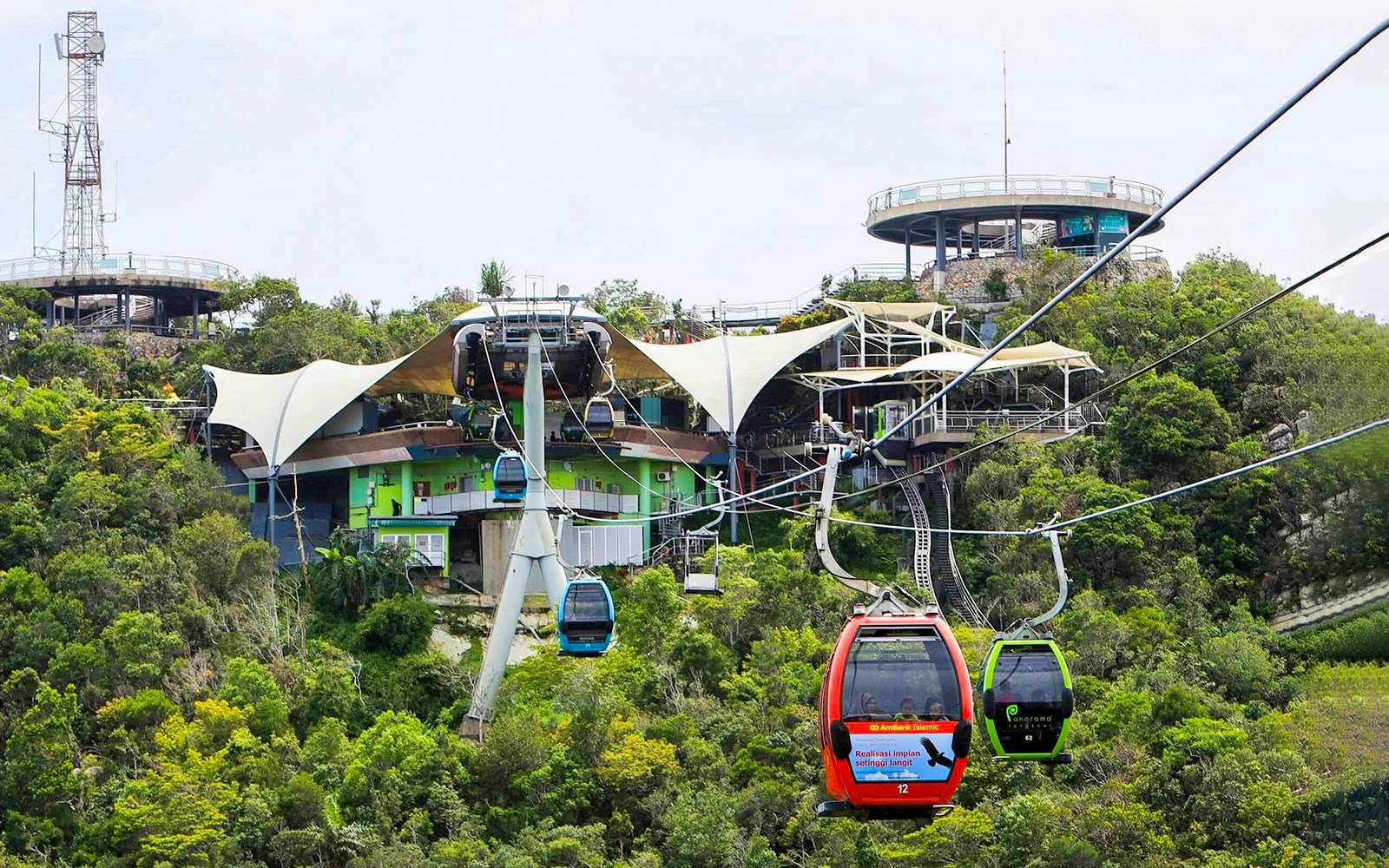 Langkawi SkyCab cable car ascending over lush rainforest with panoramic views of mountains and sea.