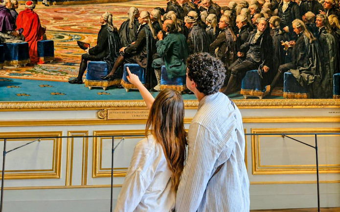 Visitors admiring a historical painting inside Versailles Palace during a private guided tour.