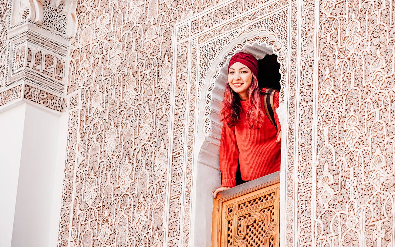 Woman looking out from a window in Ben Youssef Madrasa, Marrakech, Morocco.