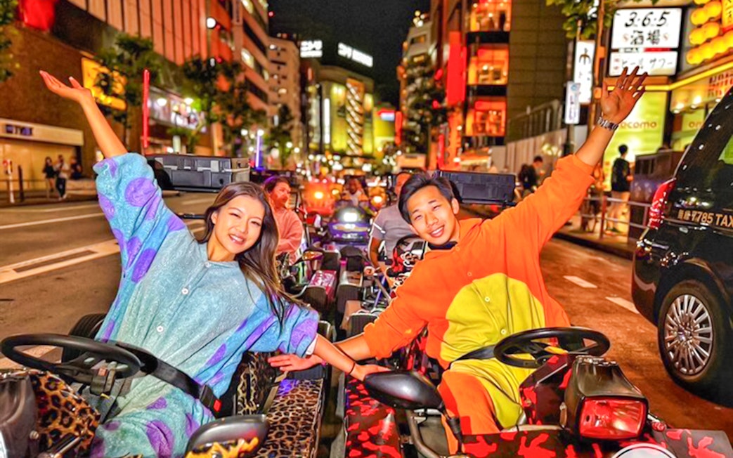Group in go-karts at night near Shibuya Crossing, Tokyo.