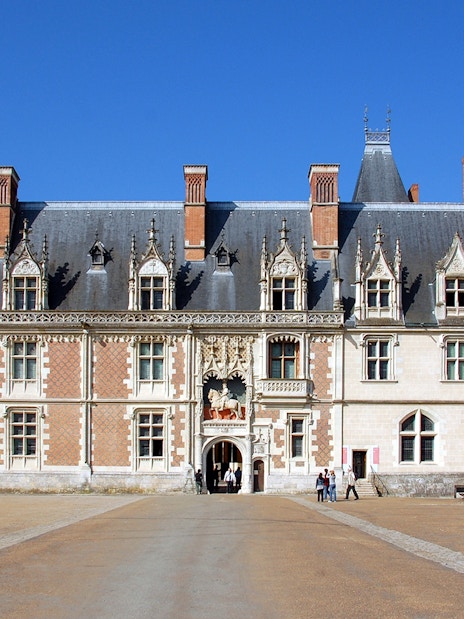 Royal Blois Castle facade with visitors entering through the main entrance.