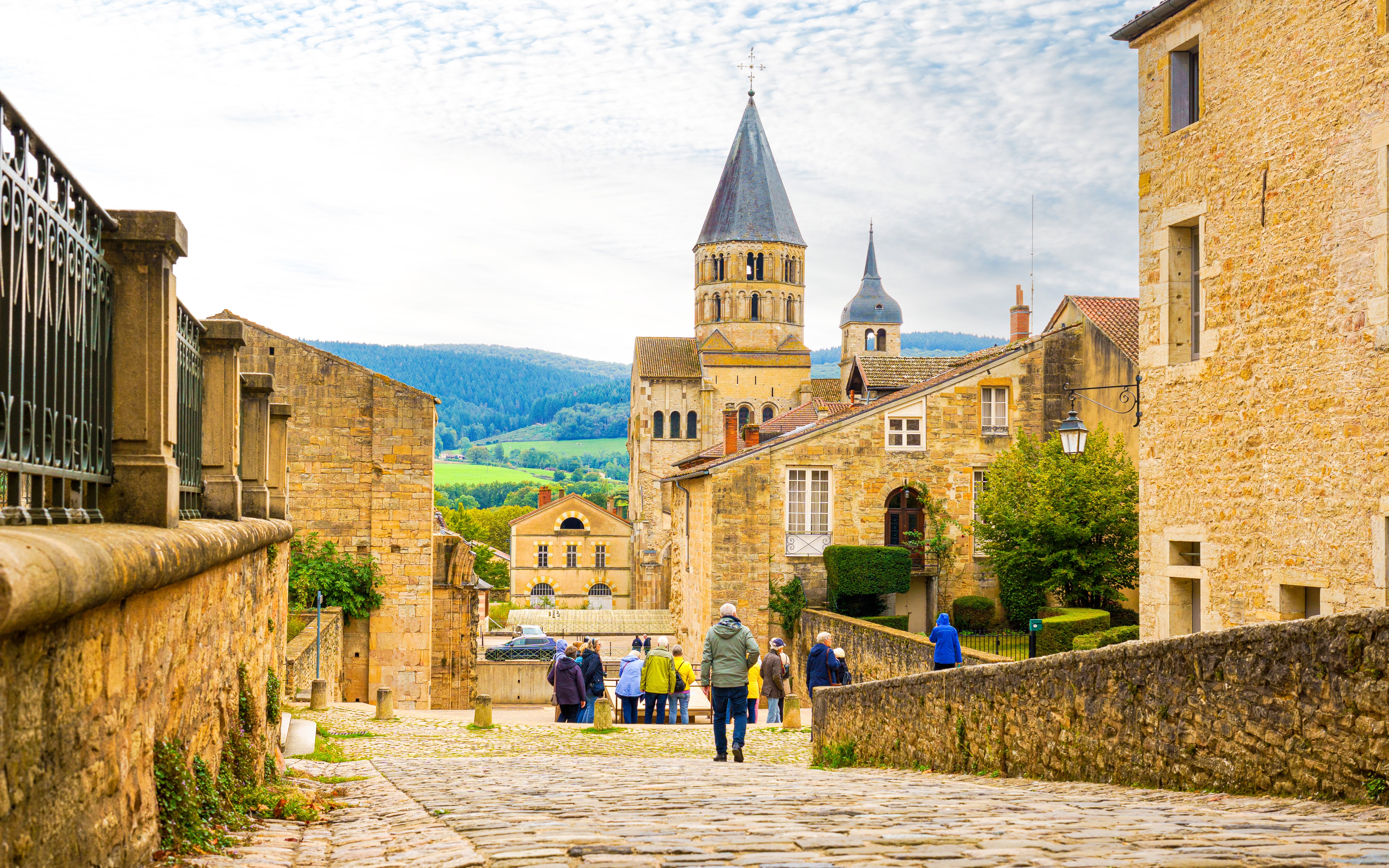 Cluny Abbey in Lyon, France with tourists walking on cobblestone street.