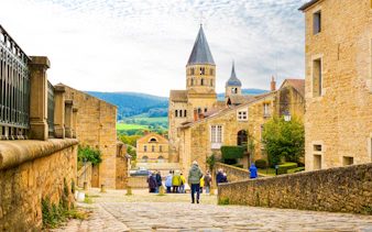 Cluny Abbey in Lyon, France with tourists walking on cobblestone street.