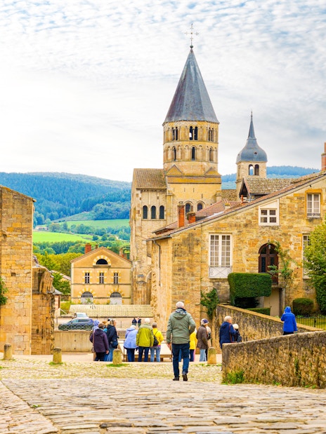 Cluny Abbey in Lyon, France with tourists walking on cobblestone street.
