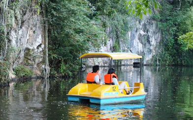 Couple on paddle boat exploring Langkawi Island's lush waterways.