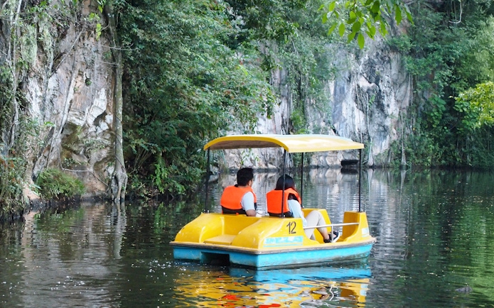 Couple on paddle boat exploring Langkawi Island's lush waterways.