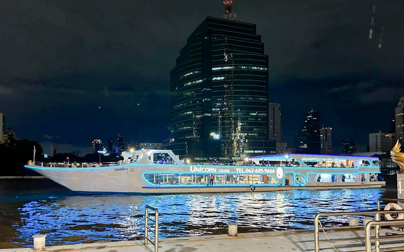Unicorn Dinner Cruise boat illuminated on Chao Phraya River, Bangkok at night.