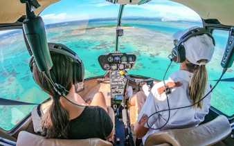 Helicopter cockpit view over turquoise ocean during panoramic tour.