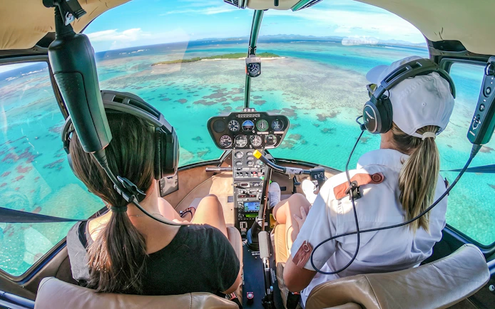 Helicopter cockpit view over turquoise ocean during panoramic tour.