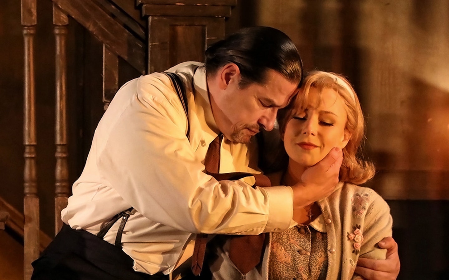 Actors embracing in a dramatic scene from Rigoletto show production.