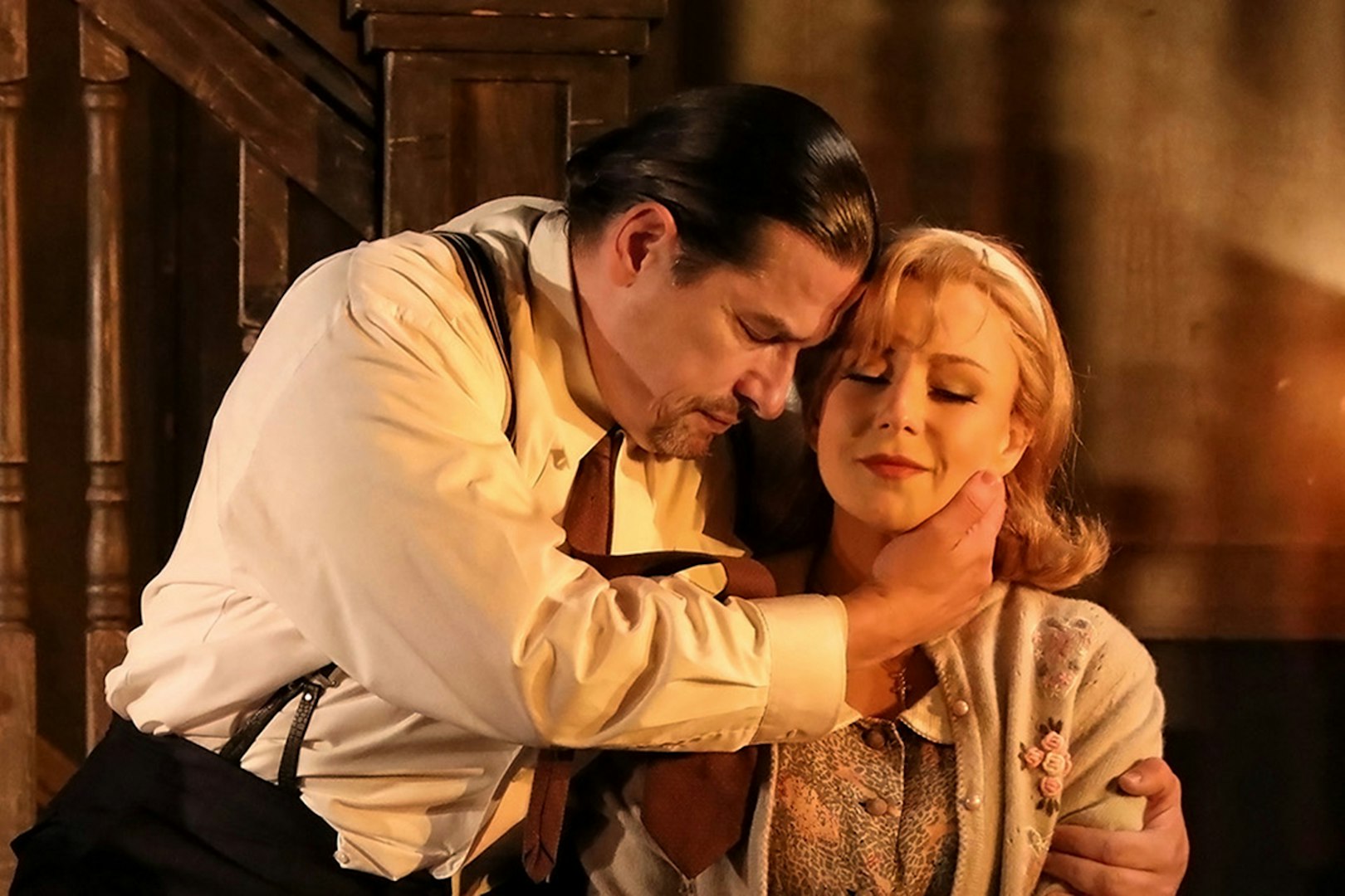 Actors embracing in a dramatic scene from Rigoletto show production.