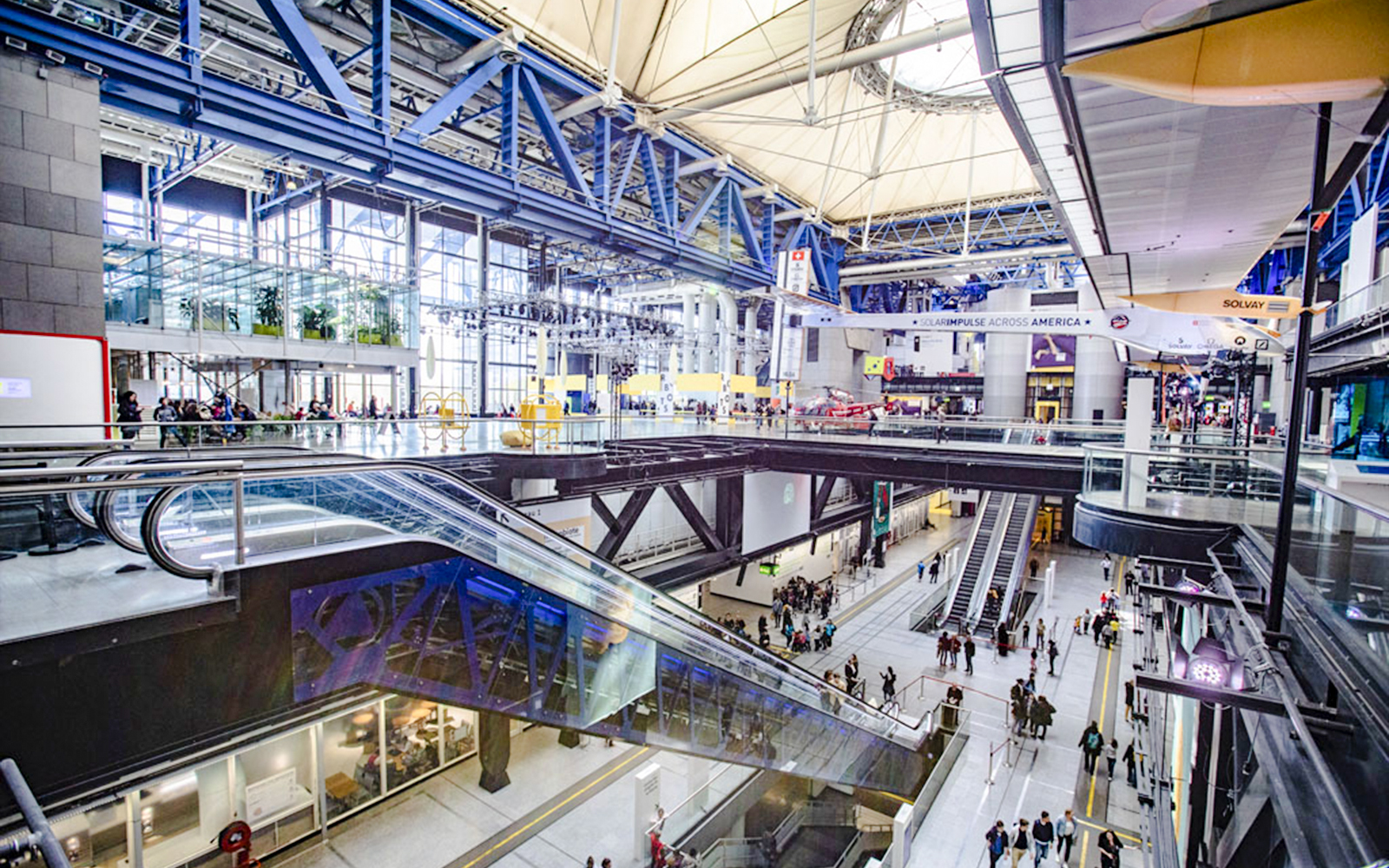 Interior view of Science & Industry Museum, Paris, featuring escalators and visitors.