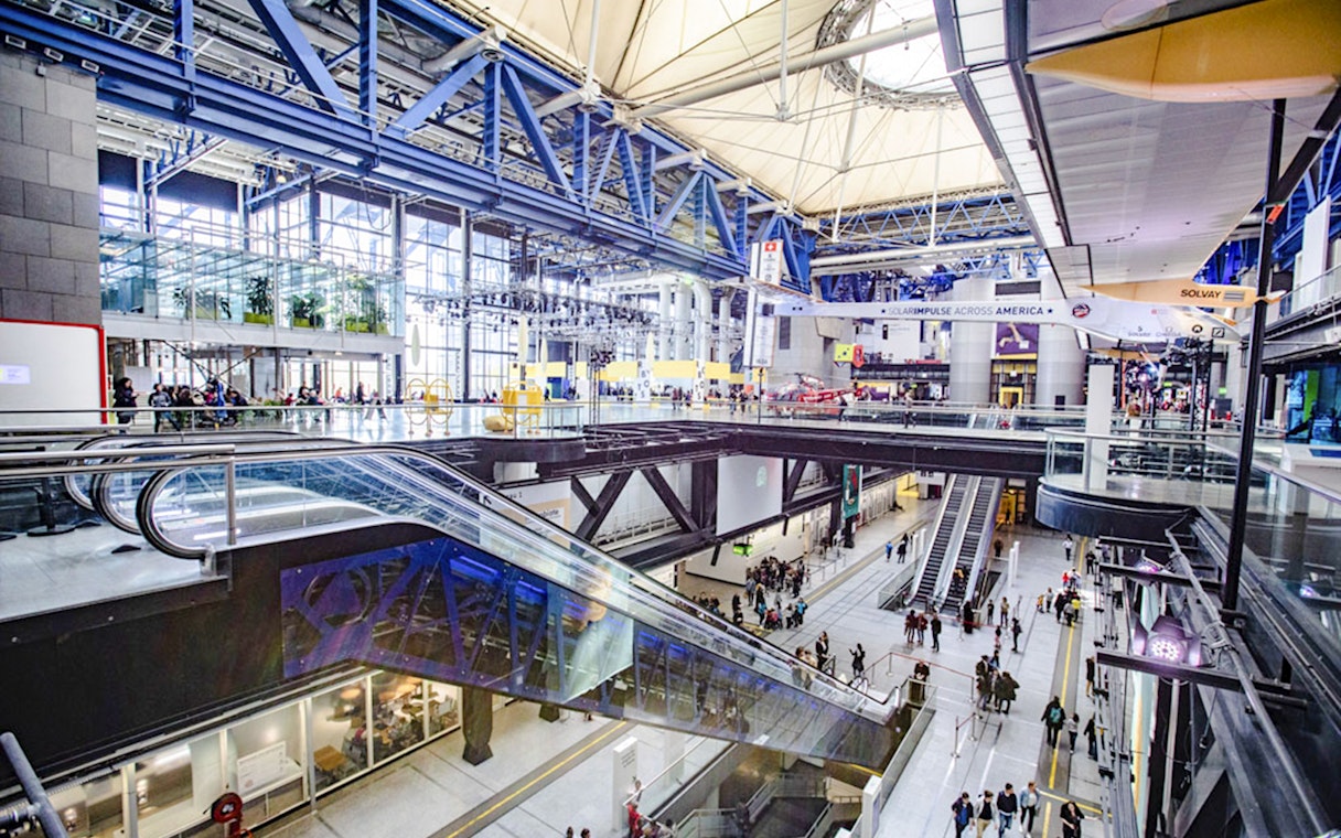 Interior view of Science & Industry Museum, Paris, featuring escalators and visitors.