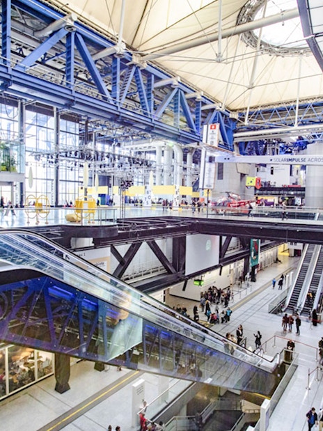 Interior view of Science & Industry Museum, Paris, featuring escalators and visitors.