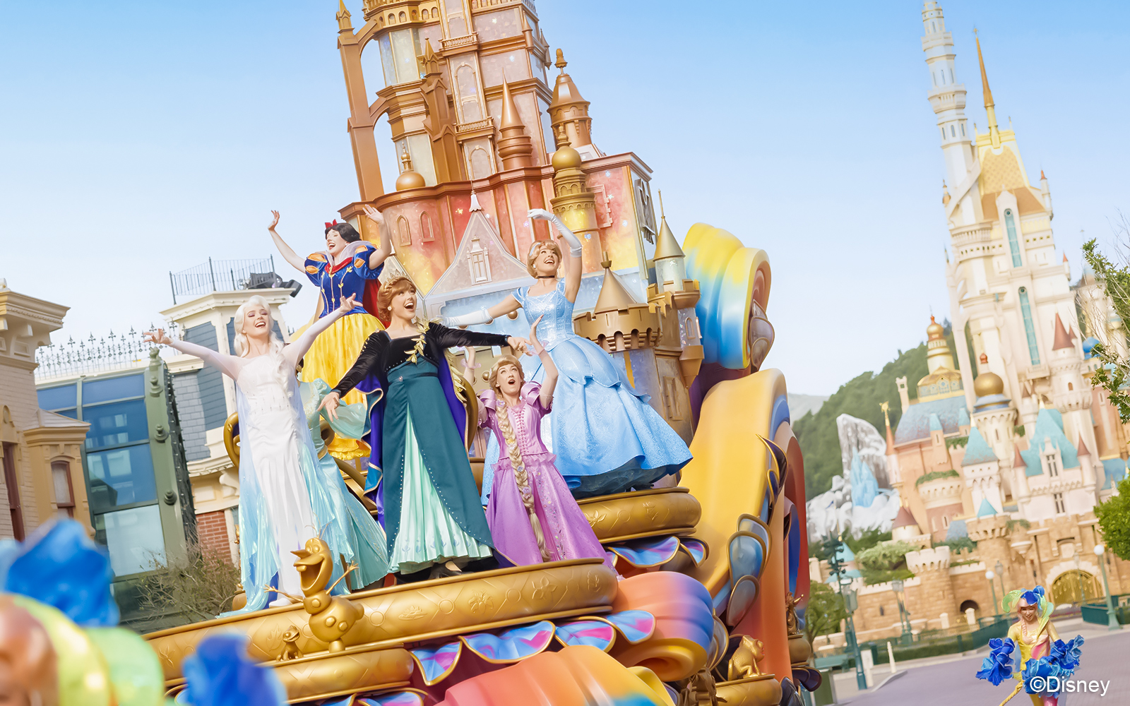 Princesses on a colorful float at Friendtastic! Parade with castle backdrop.