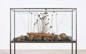 Casa Mila Anselm Kiefer exhibition sculpture with boat and rocks in glass case.