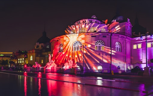 Illuminated building with colorful light projections at night in Budapest, Hungary.