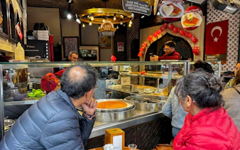 Customers observing traditional Turkish desserts being prepared in an Istanbul shop.