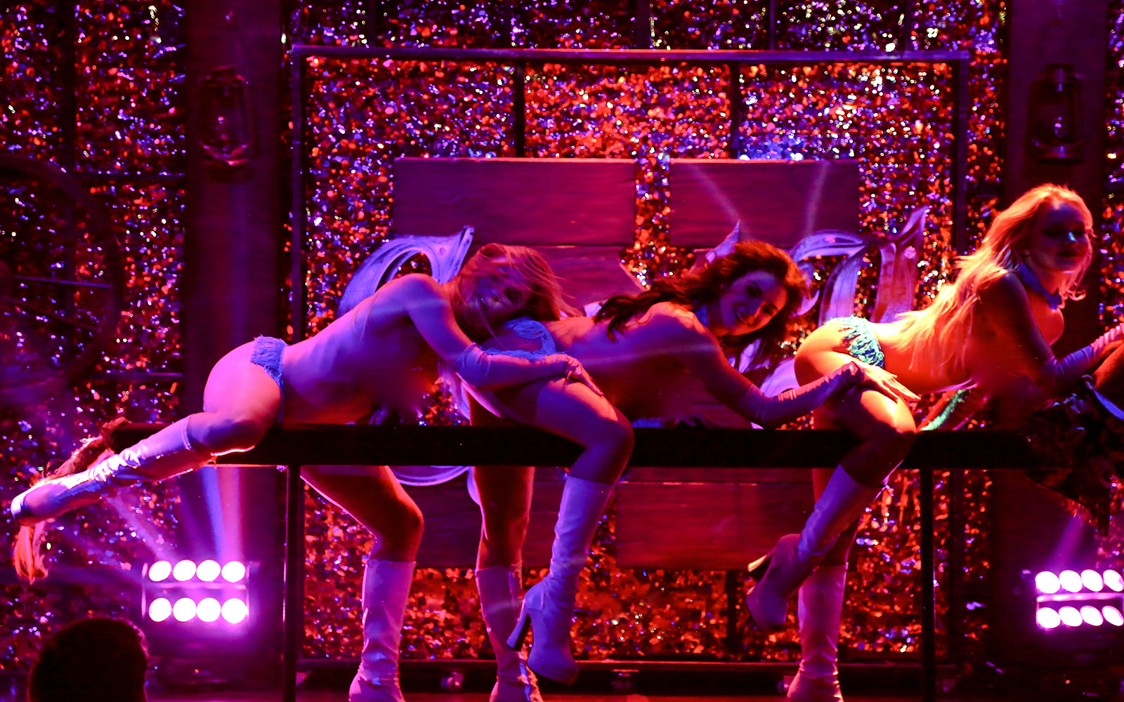 Vegas stage performance of Kick'n Topless Revue with dancers in vibrant lighting.