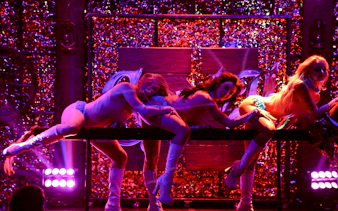 Vegas stage performance of Kick'n Topless Revue with dancers in vibrant lighting.