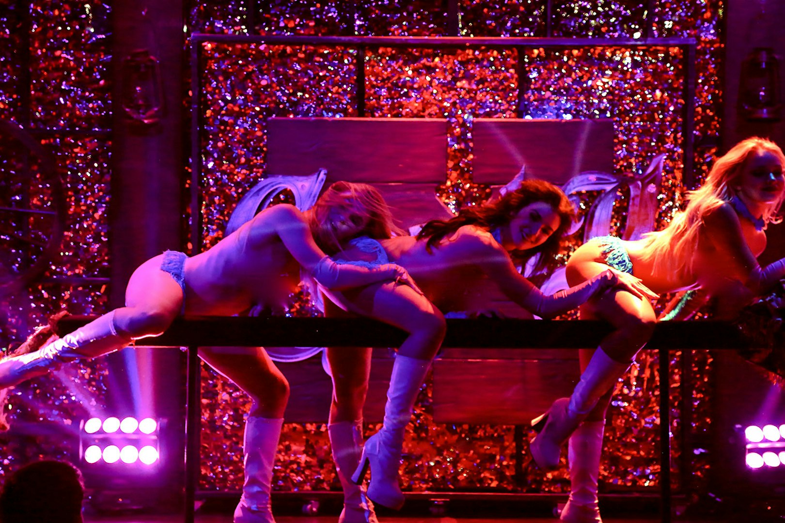 Vegas stage performance of Kick'n Topless Revue with dancers in vibrant lighting.