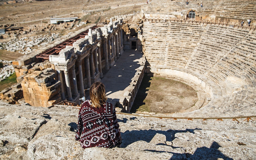 Woman traveler overlooking the ancient amphitheater in Hierapolis, Turkey.