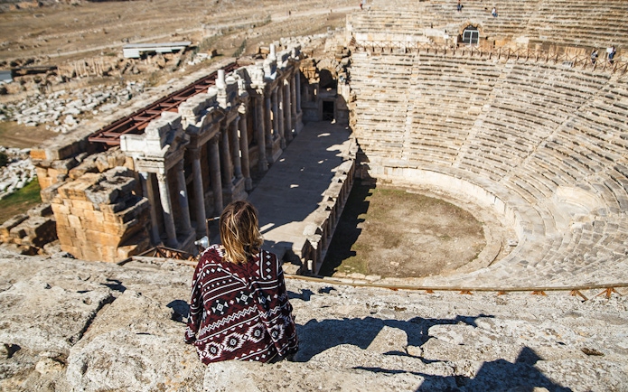 Woman traveler overlooking the ancient amphitheater in Hierapolis, Turkey.