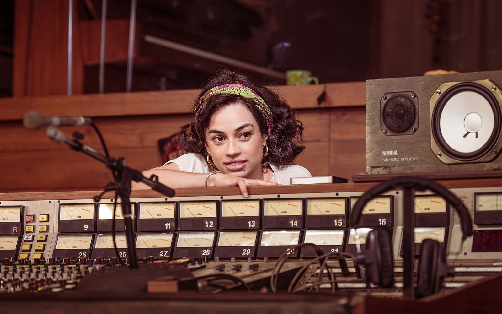 Recording studio with woman leaning on soundboard, featuring stereophonic equipment.