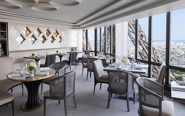 Dining area with set tables inside Eiffel Tower overlooking Paris.