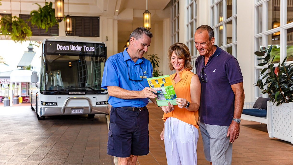 Tourists with guide in front of Down Under Tours bus, Kuranda Scenic Railway, Queensland.
